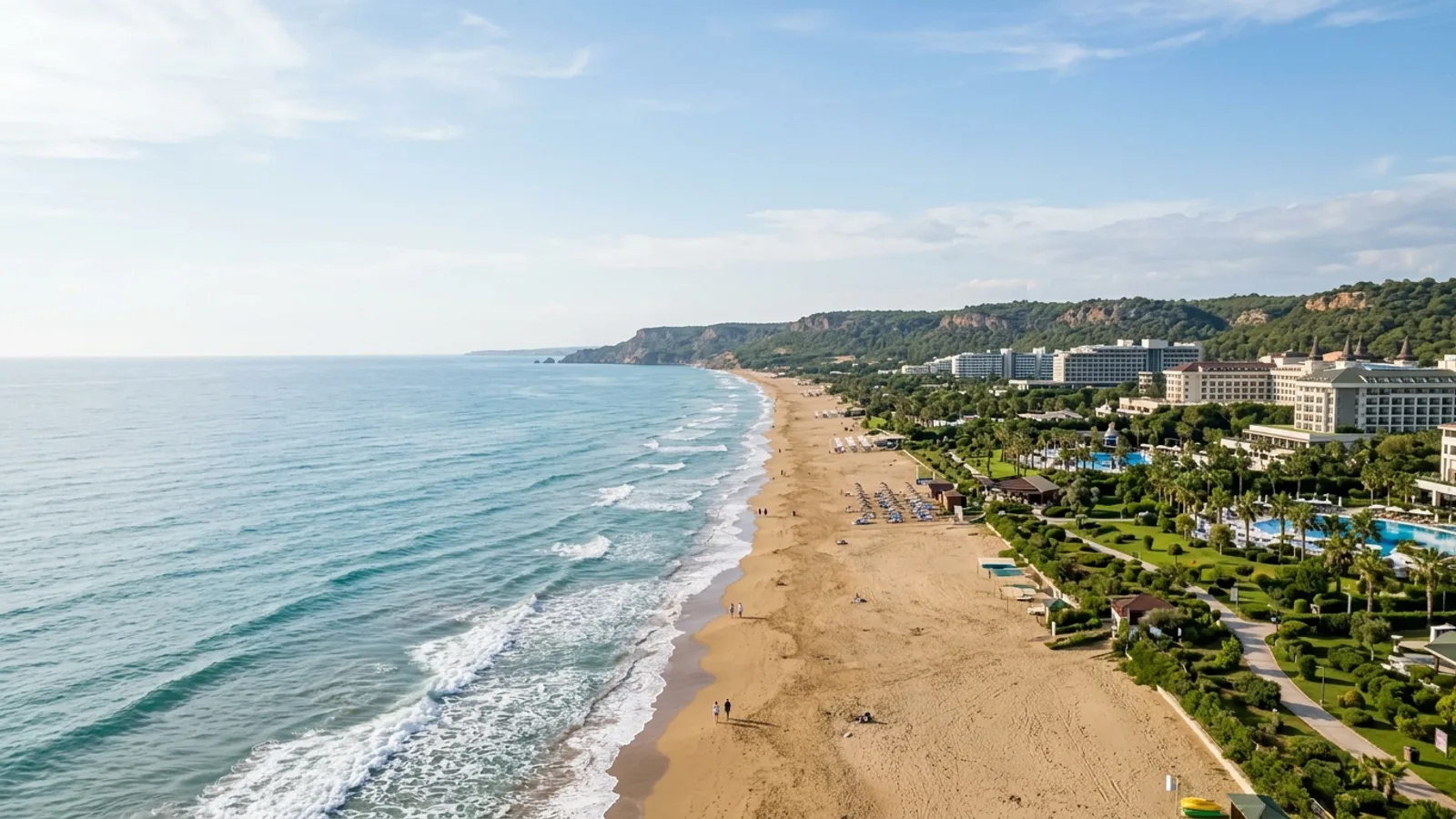 Lara, Türkiye — the long straight sandy beach at Lara east of Antalya, with low cliffs behind the shore and large resort hotels set back among landscaped gardens.