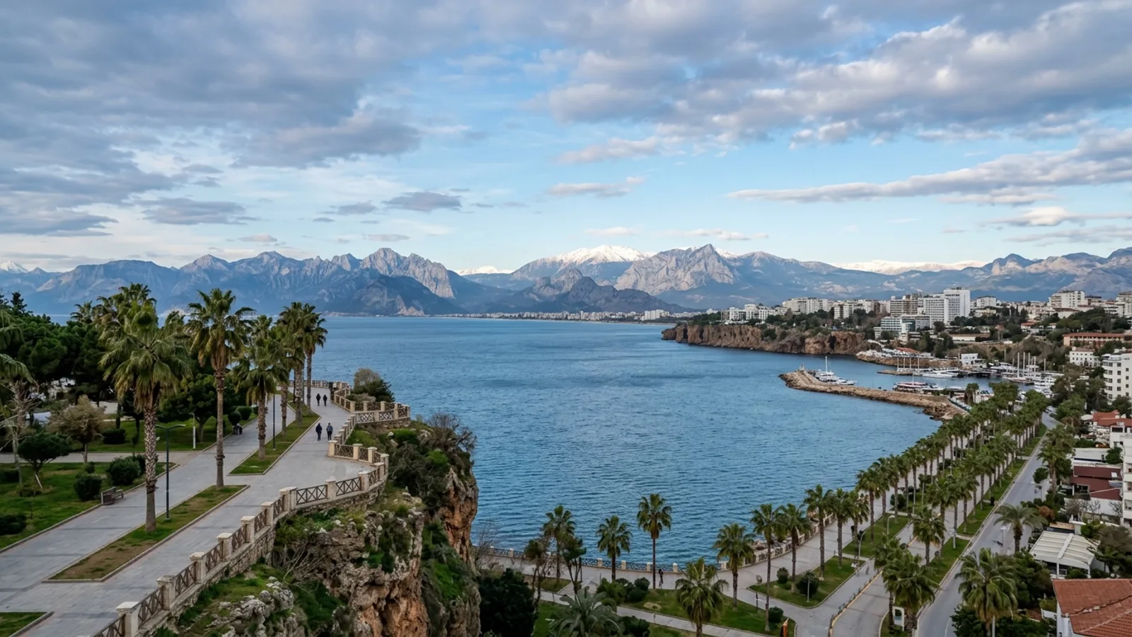 Antalya City Centrum, Türkiye — the modern seafront of Antalya city, palm-lined boulevards on the cliff top and the snow-topped Taurus mountains rising across the bay.