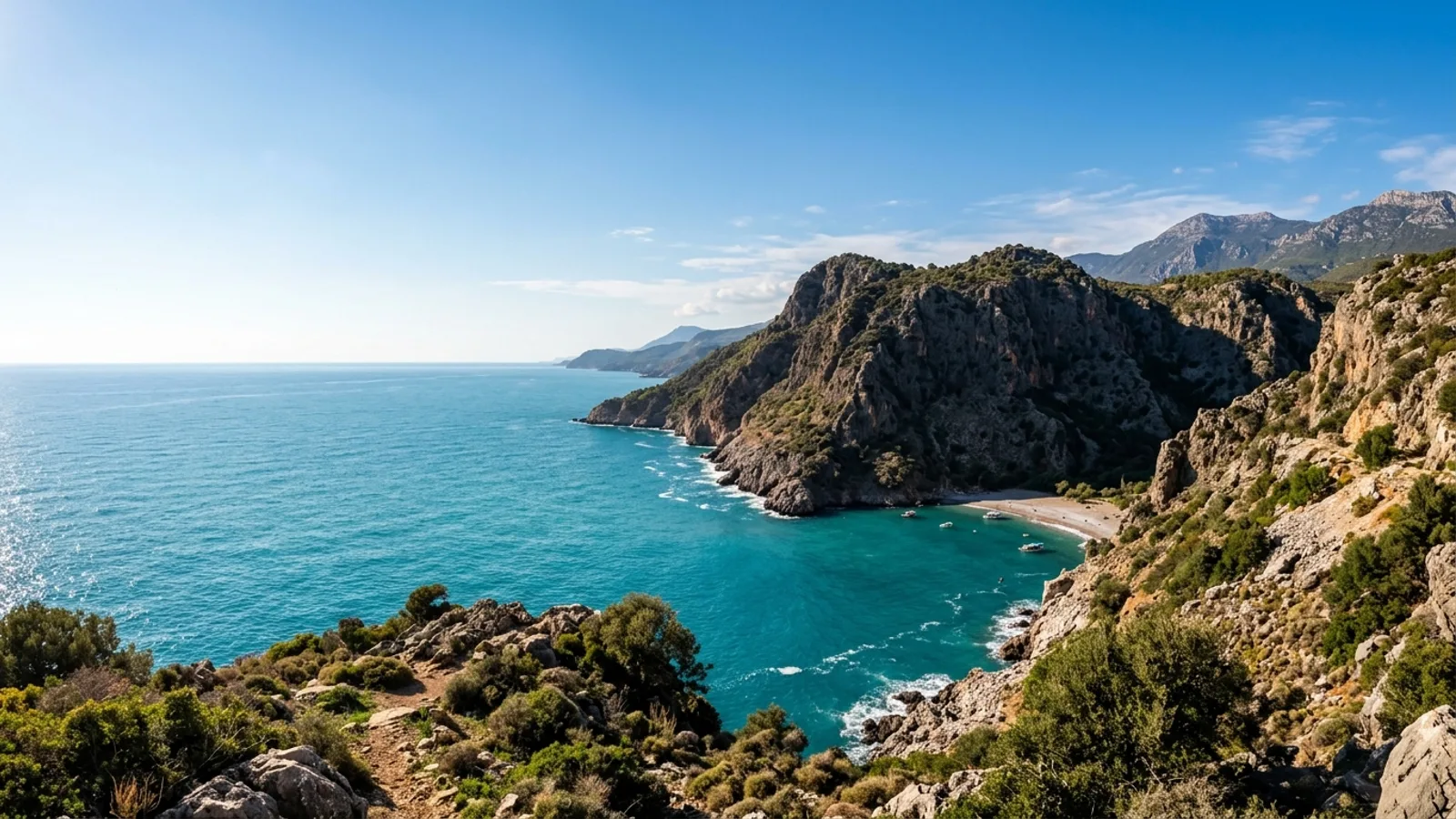 Karaburun, Türkiye — the rocky headland at Karaburun on the Antalya coast, dark cliffs meeting clear blue water with a small beach in the shelter of the point.