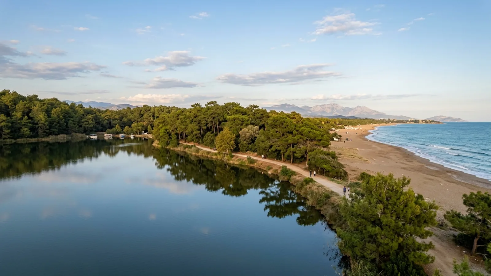 Titreyengol, Türkiye — the small lake at Titreyengol near Side, still water reflecting a surrounding pine forest a short walk from a sandy Mediterranean beach.