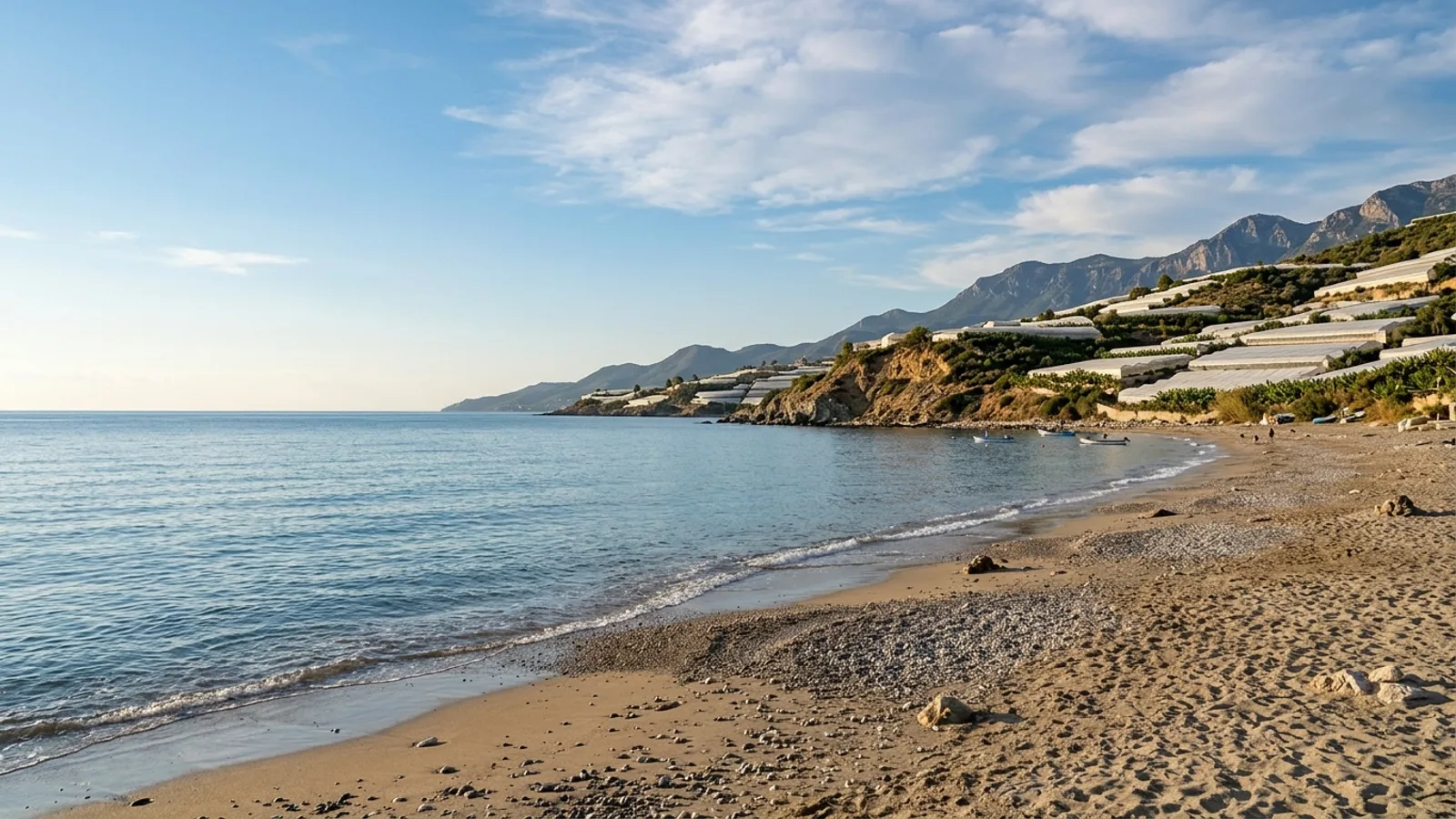 Turkler, Türkiye — the shore at Turkler on the Alanya coast, a quiet sand and pebble beach with banana greenhouses on the slopes behind.